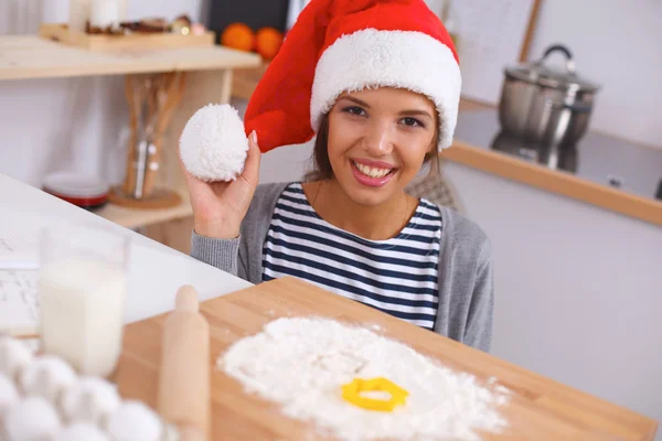 Lykkelig ung kvinde smilende glad for at have det sjovt med juleforberedelser iført Santa hat - Stock-foto