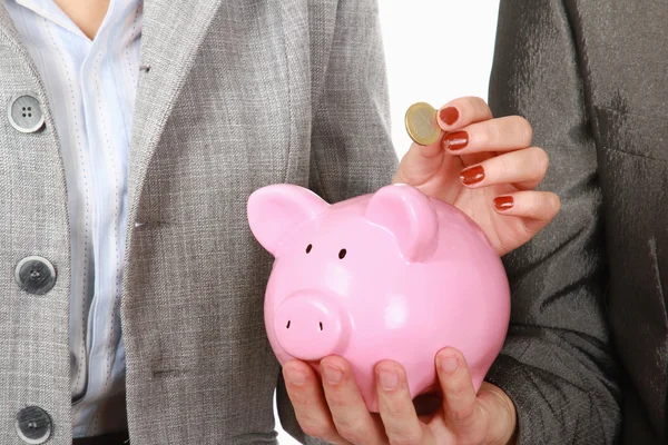 Eine Geschäftsfrau und ein Mann legen eine Münze in ein Sparschwein, isoliert auf weißem Hintergrund — Stockfoto