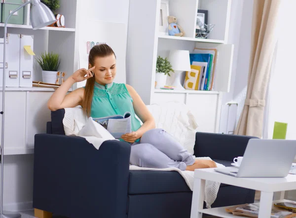 Glad ung kvinna läser sagobok på soffan hemma — Stockfoto