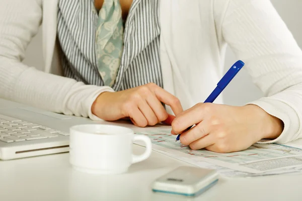 Eine Frau am Schreibtisch schreibt auf ein Papier, isoliert auf weiß. — Stockfoto