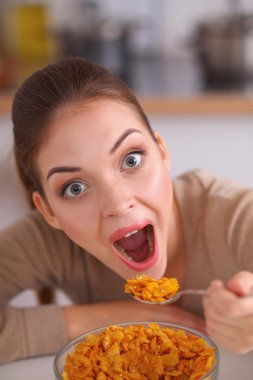 Gülümseyen çekici kadın mutfağın içinde kahvaltı yapıyor.