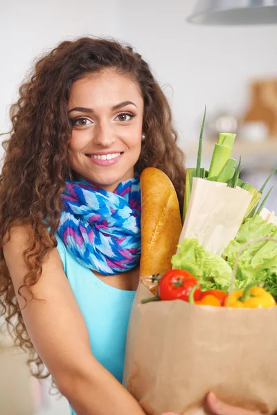 Young woman holding grocery shopping bag with vegetables Standing in the kitchen. — Stock Photo, Image