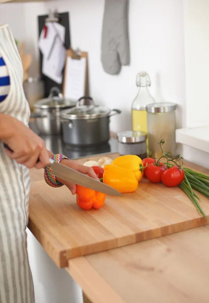 Ung kvinna skära grönsaker i köket — Stockfoto