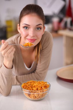 Gülümseyen çekici kadın mutfağın içinde kahvaltı yapıyor.