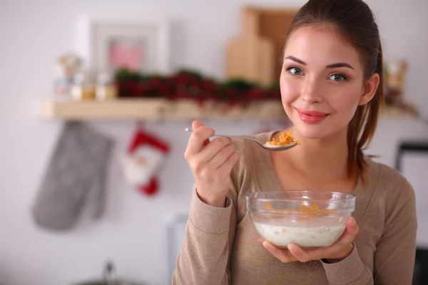 Gülümseyen çekici kadın mutfağın içinde kahvaltı yapıyor.