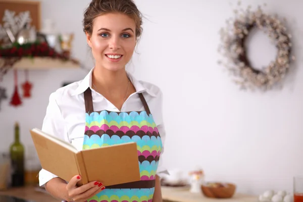 Mujer joven leyendo libro de cocina en la cocina, buscando receta —  Fotos de Stock