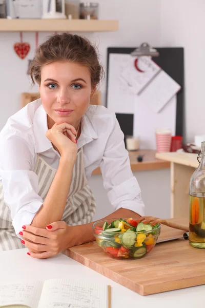 Mujer joven comiendo ensalada fresca en la cocina moderna — Foto de Stock