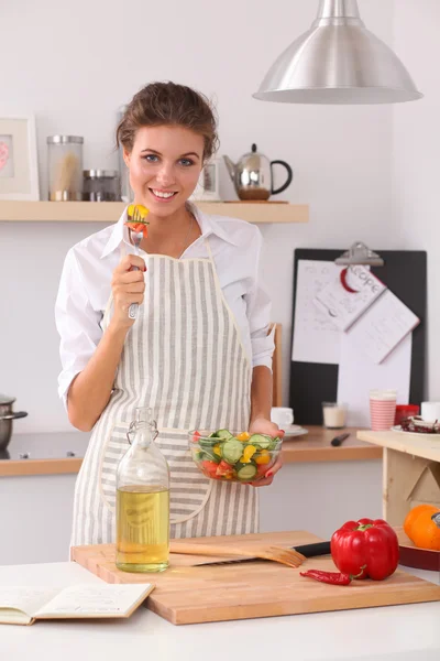 Mujer joven comiendo ensalada fresca en la cocina moderna — Foto de Stock