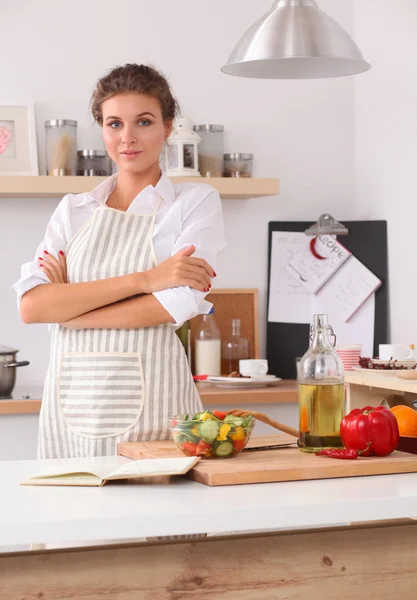 Glimlachende jonge vrouw in de keuken, geïsoleerd op kerst achtergrond — Stockfoto