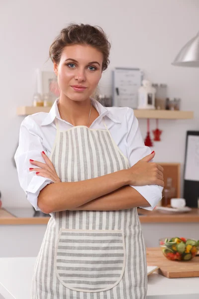 Glimlachende jonge vrouw in de keuken, geïsoleerd op kerst achtergrond — Stockfoto