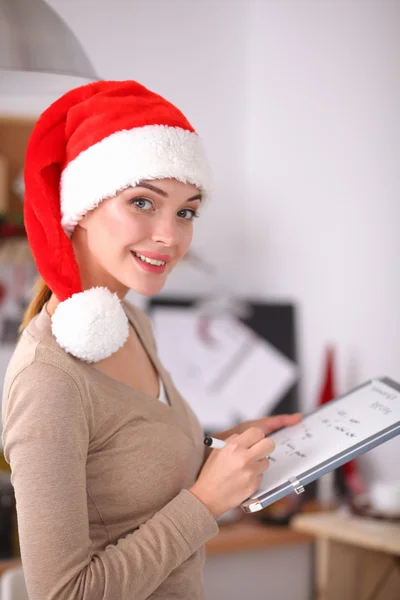 Glimlachende jonge vrouw in de keuken, geïsoleerd op kerst achtergrond — Stockfoto