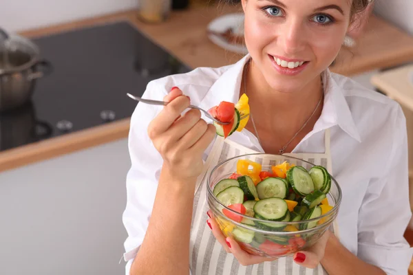 Ung kvinna äter färsk sallad i modernt kök — Stockfoto