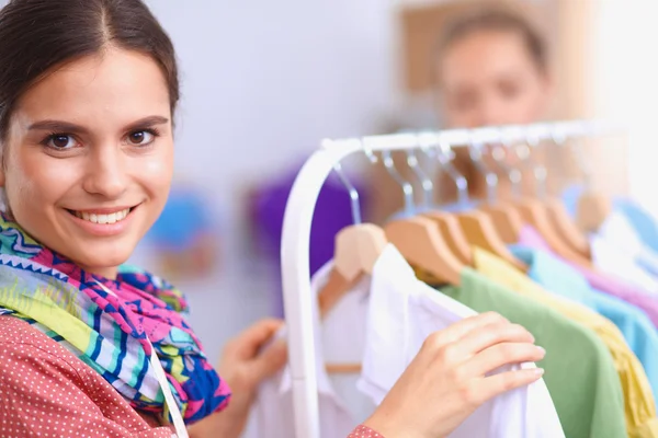 Beautiful young stylist near rack with hangers — Stock Photo, Image