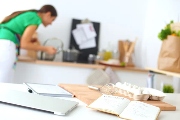 Sorridente giovane donna in cucina, isolata sullo sfondo — Foto Stock