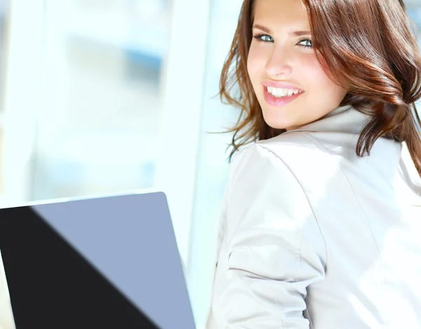 Young smiling woman sitting with laptop computer and credit card in her hand. — Stock Photo, Image