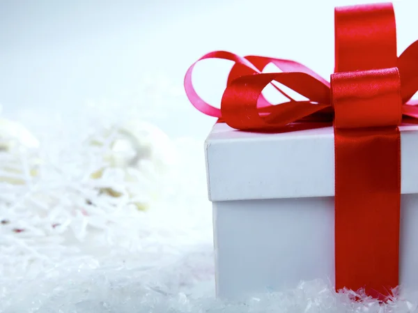 Scatola regalo decorativo bianco con un fiocco rosso uno sfondo bokeh . — Foto Stock