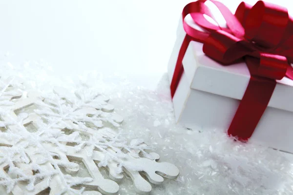 Decorative white gift box with a red bow a background bokeh. — Stock Photo, Image