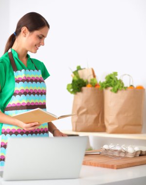 Mutfakta gülümseyen genç bir kadın, arka planda soyutlanmış.