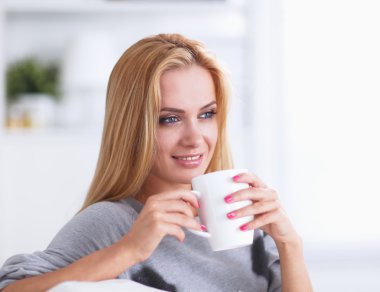 evde kanepenin üzerine bir fincan genç güzel kadın