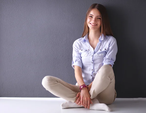 Mujer joven sentada en el suelo cerca de la pared oscura — Foto de Stock