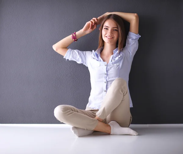 Jeune femme assise sur le sol près du mur sombre — Photo