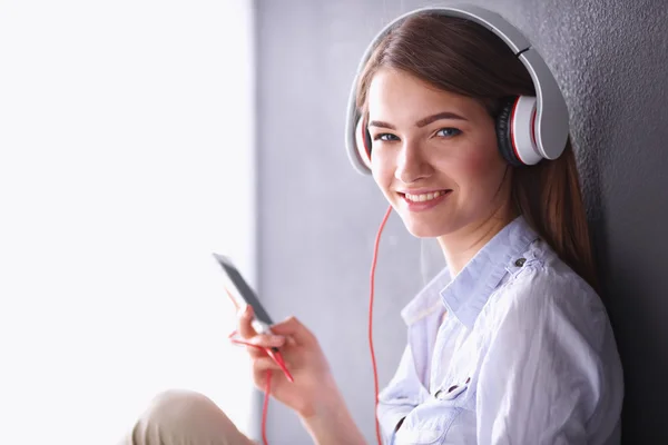 Chica sonriente con auriculares sentados en el suelo —  Fotos de Stock