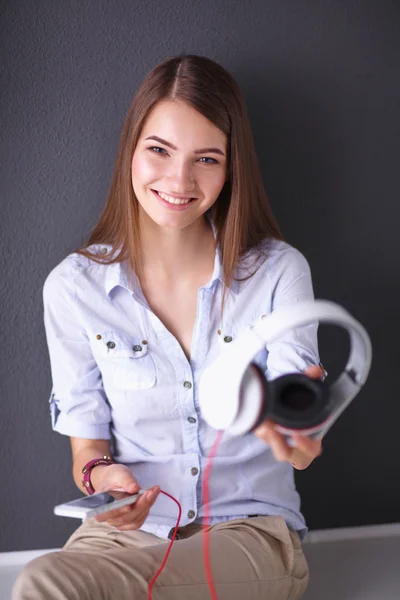 Ragazza sorridente con cuffie isolate su sfondo grigio — Foto Stock