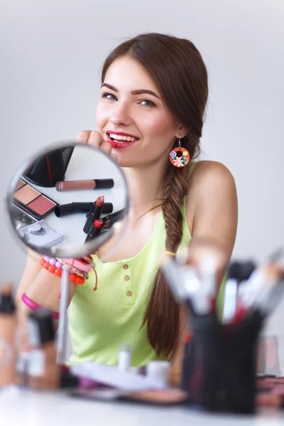 Joven hermosa mujer haciendo maquillaje cerca del espejo — Foto de Stock