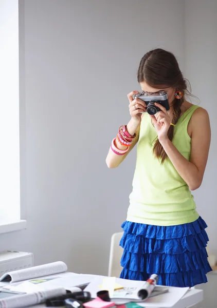 Beautiful young woman with camera standing near window — Stock Photo, Image
