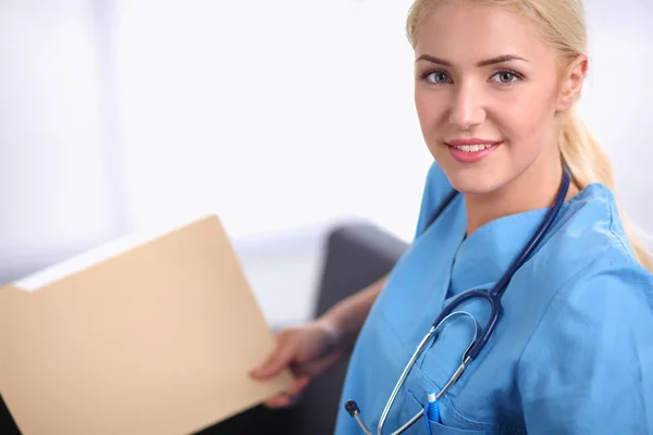 Portrait of a happy young doctor sitting on the sofa with folder — Stock Photo, Image