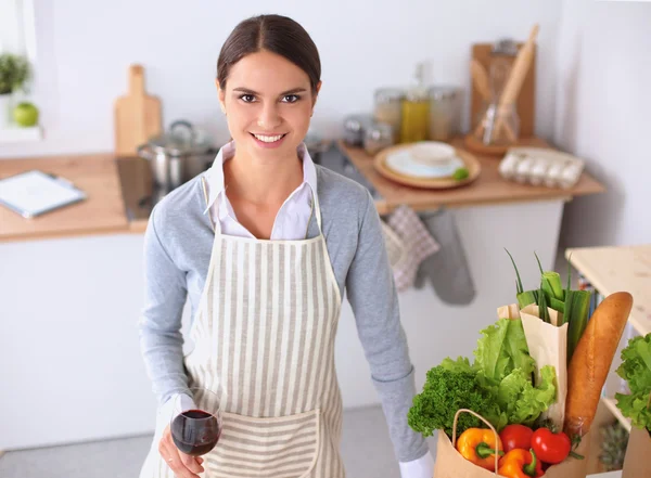 Mujer con bolsas de compras en la cocina en casa, de pie cerca del escritorio — Foto de Stock