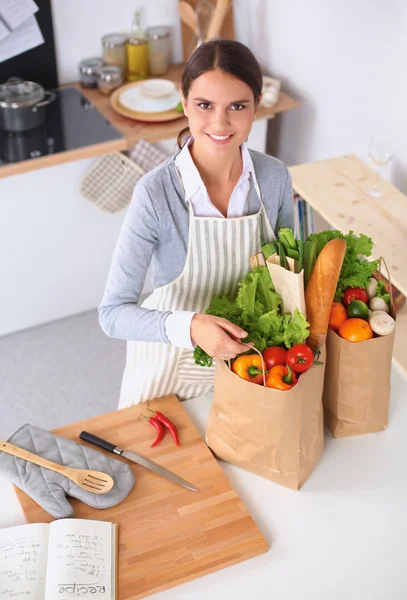 Vrouw met boodschappentassen in de keuken thuis, bij het bureau — Stockfoto