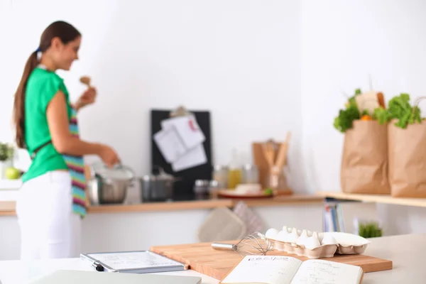 Mujer joven sonriente en la cocina, aislada en el fondo —  Fotos de Stock