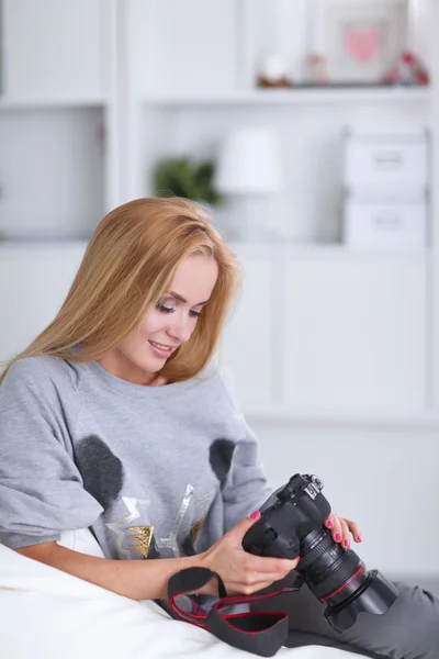 Woman sitting on a sofa in her house with camera — Stock Photo, Image