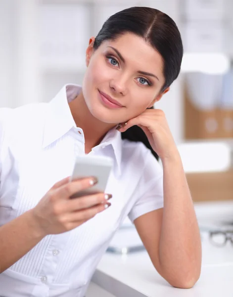 Empresaria enviando mensaje con teléfono inteligente sentado en la oficina — Foto de Stock