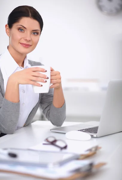 Joven mujer de negocios sentada en el escritorio con taza en la oficina —  Fotos de Stock