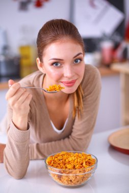 Gülümseyen çekici kadın mutfağın içinde kahvaltı yapıyor.