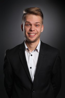 Gri arka plan üzerinde izole gülümseyen genç adam portresi