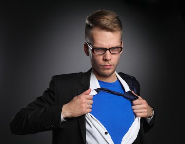 Genç işadamı hareket ve bir süper kahraman gibi gömleğini, yırtılma gri arka plan üzerinde izole