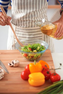 Gülümseyen genç kadın taze salata hazırlıyor.