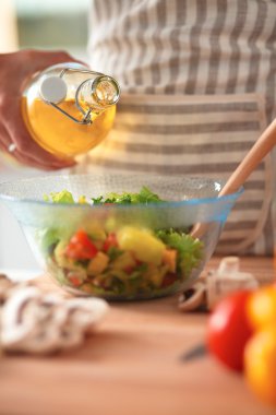 Gülümseyen genç kadın taze salata hazırlıyor.