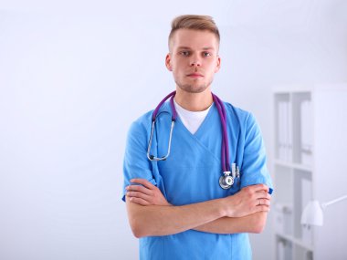 Steteskoplu doktor ayakta, çapraz kollu, beyaz arka planda izole.