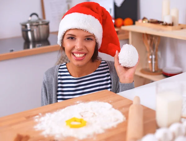 Lykkelig ung kvinde smilende glad for at have det sjovt med juleforberedelser iført Santa hat - Stock-foto