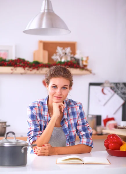 Glimlachende jonge vrouw in de keuken, geïsoleerd op kerst achtergrond — Stockfoto