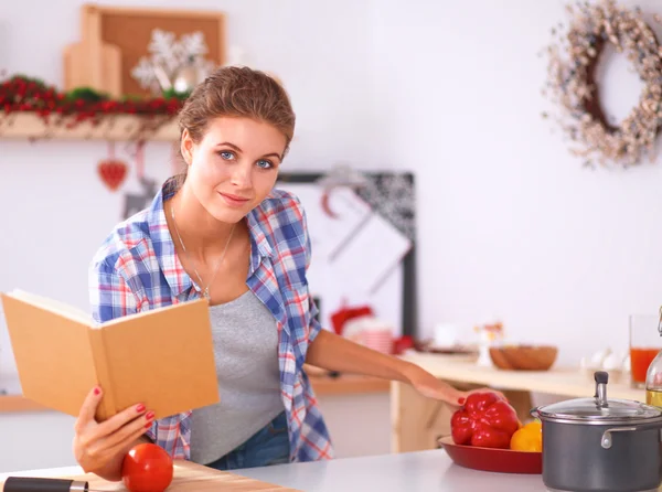 Jovem mulher lendo livro de receitas na cozinha, à procura de receita — Fotografia de Stock