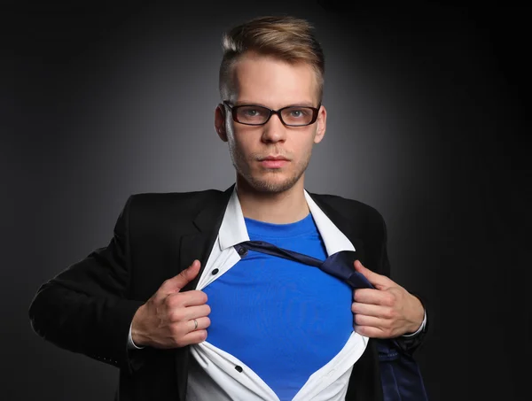 Joven hombre de negocios actuando como un súper héroe y rasgando su camisa, aislado sobre un fondo gris — Foto de Stock