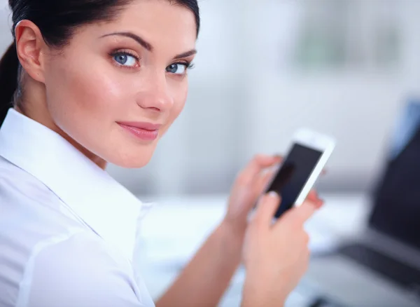 Empresaria enviando mensaje con teléfono inteligente sentado en la oficina — Foto de Stock