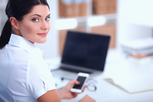 Businesswoman sending message with smartphone sitting in the office — Stock Photo, Image