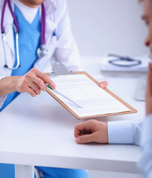 Médico macho dando pasta paciente com papel em seu escritório, isolado — Fotografia de Stock