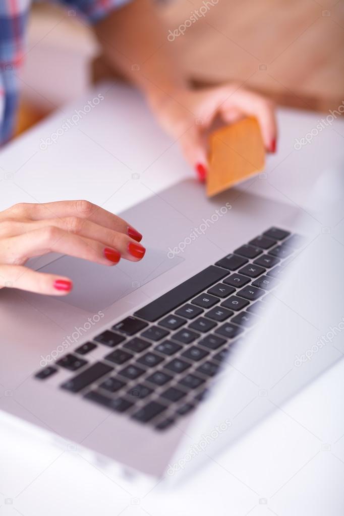 Smiling woman online shopping using computer and credit card in kitchen